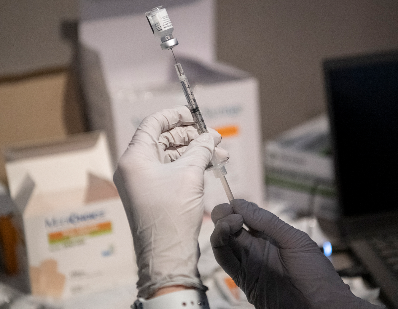 Masked provider with COVID vaccine syringe
