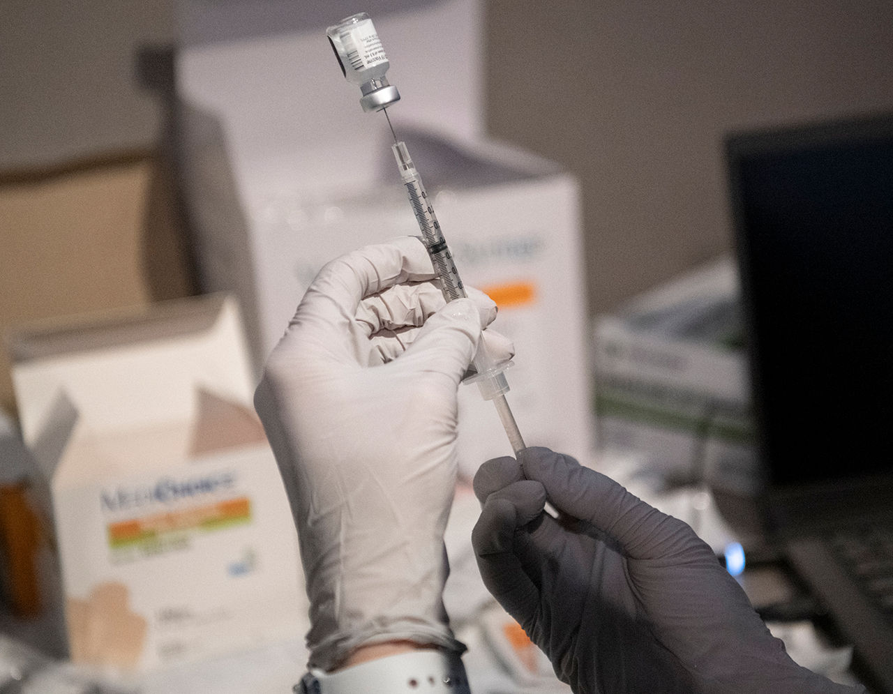 Masked provider with COVID vaccine syringe