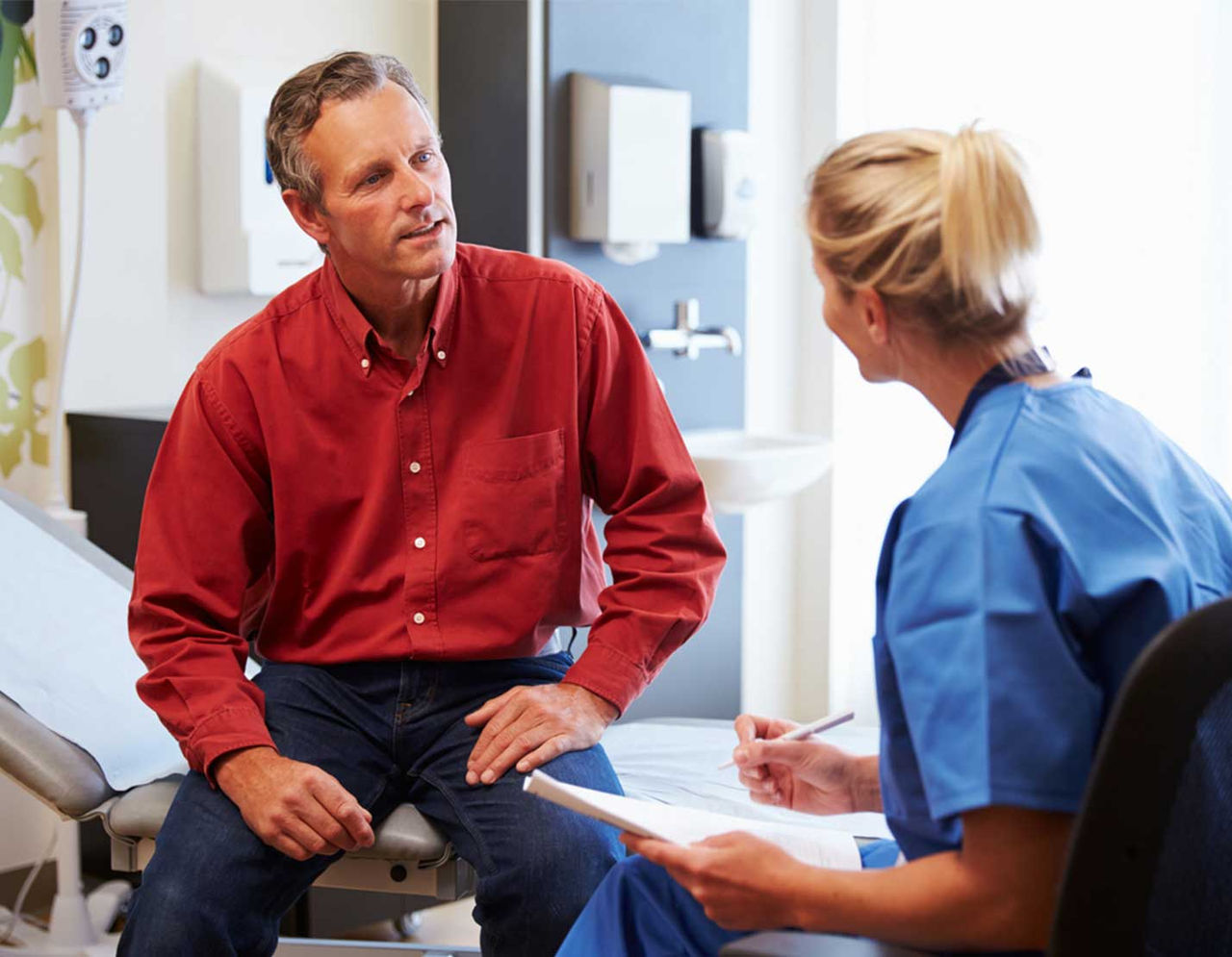 man talking with female clinician in exam room