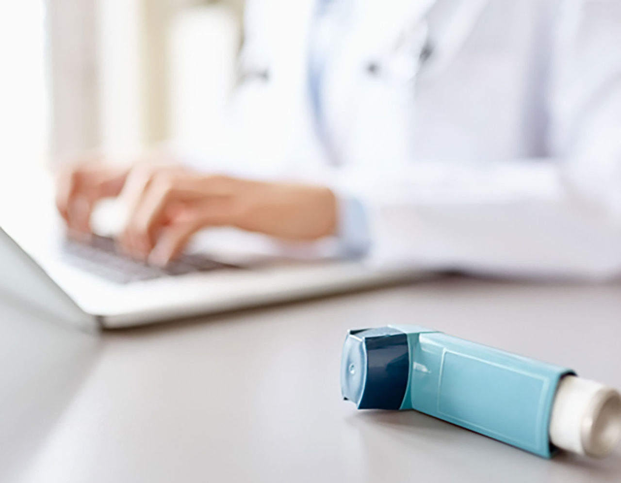 Doctor on computer with inhaler on desk