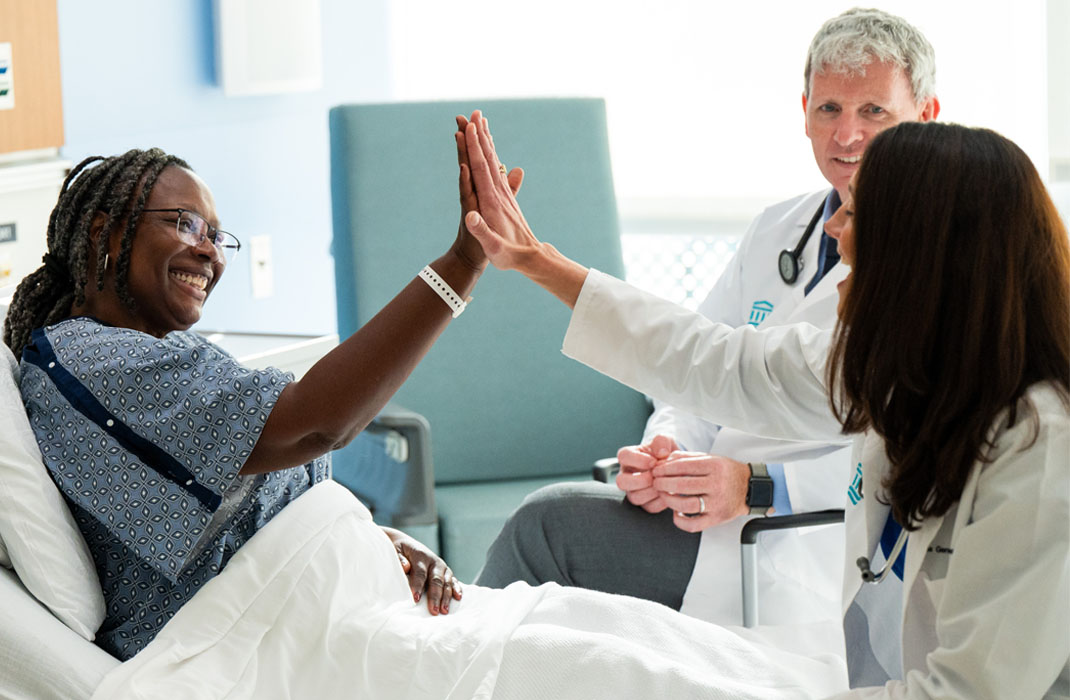 Tomas Neilan, MD, MPH and Kerry Reynolds, MD with a patient in a hospital room.