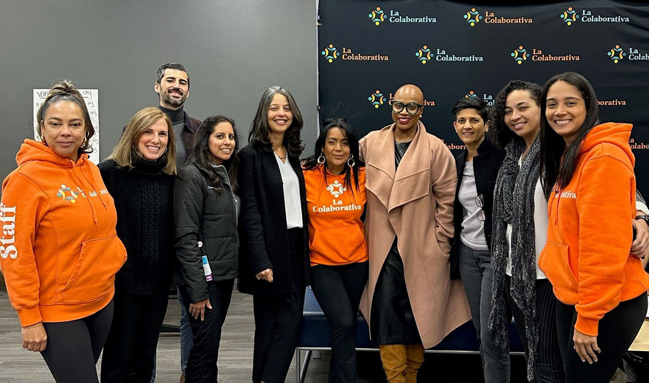 A group of 10 people smiling together for a photo. The group is made up of leaders from La Colaborativa and Mass General Brigham with Congresswoman Ayanna Pressley.