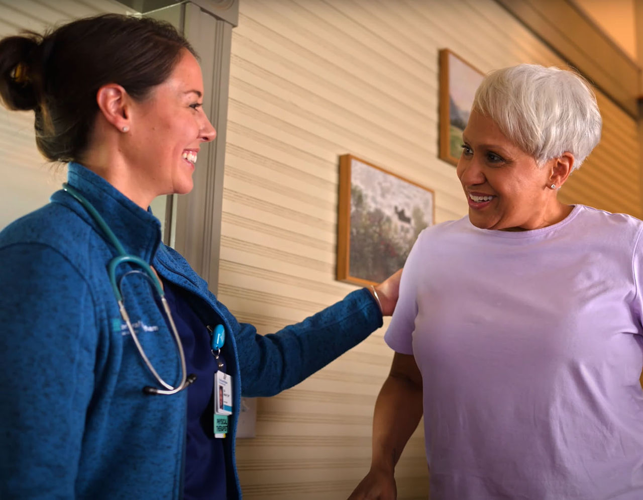 Patient smiles at the camera while a provider in scrubs stands in the background