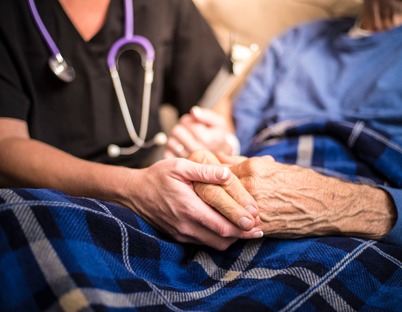 A nurse visiting an elderly male patient who is receiving palliative care at home.