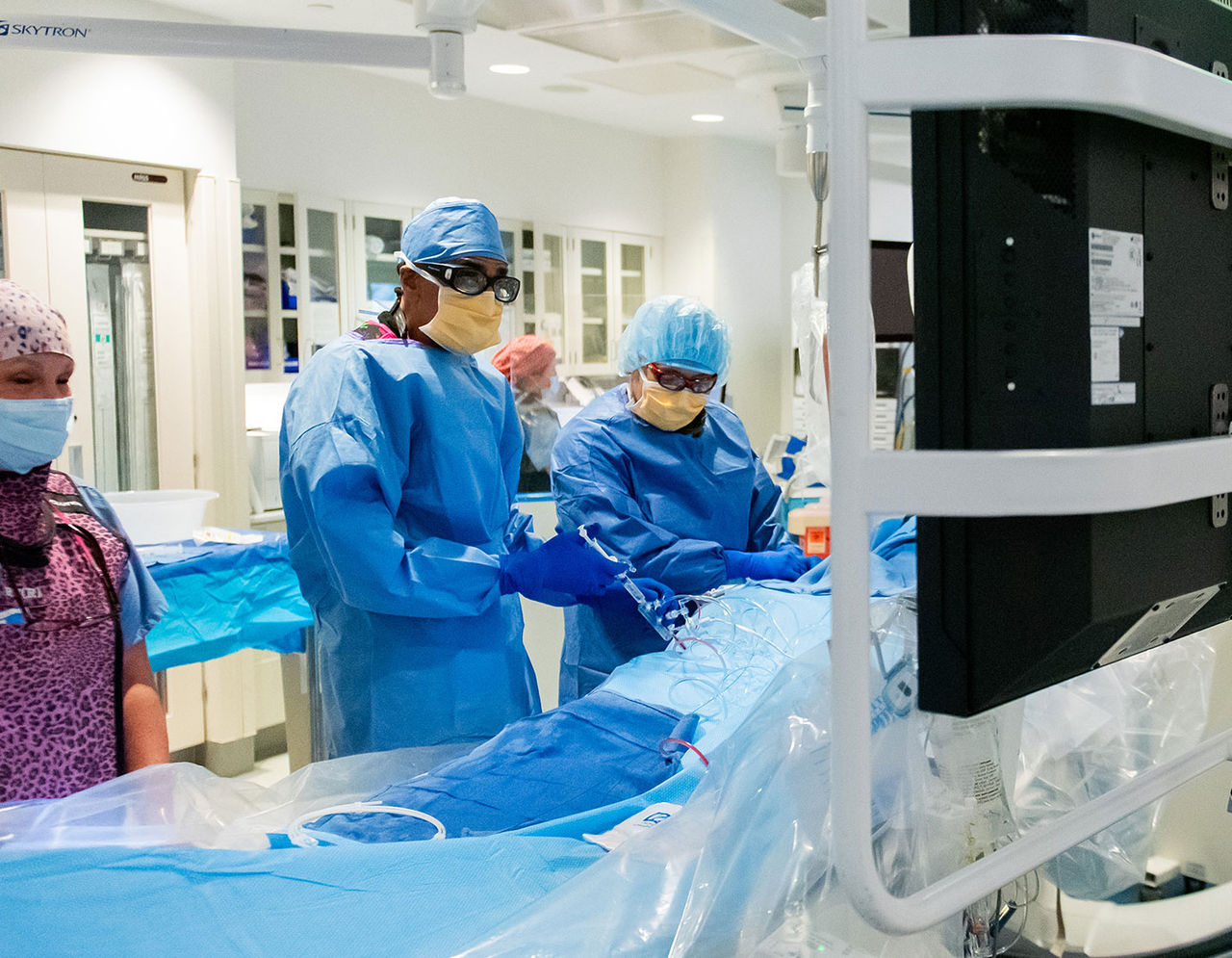 members of the heart performing surgery on patient in operating room while viewing monitor