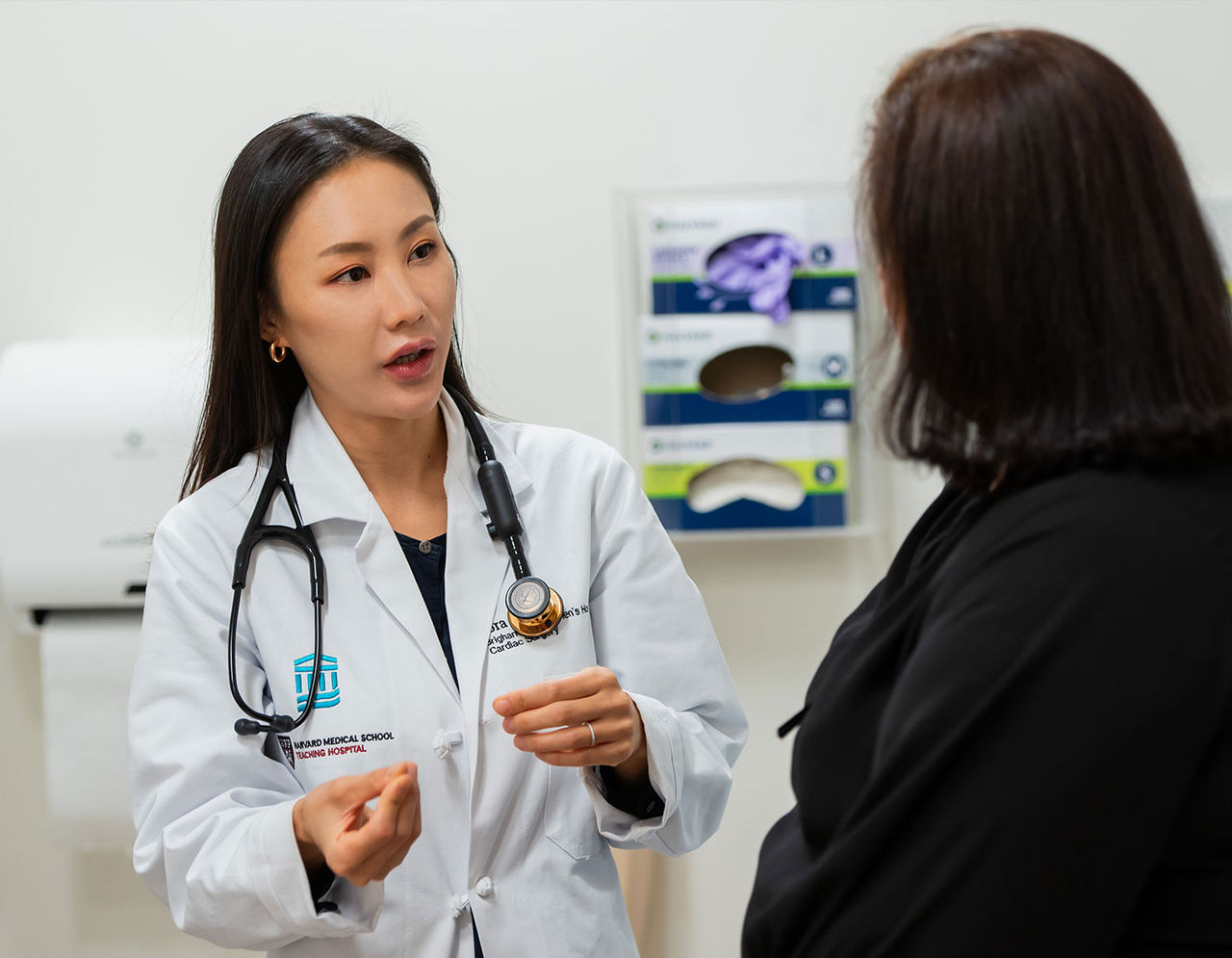 female heart provider in lab coat talking to female patient in exam room