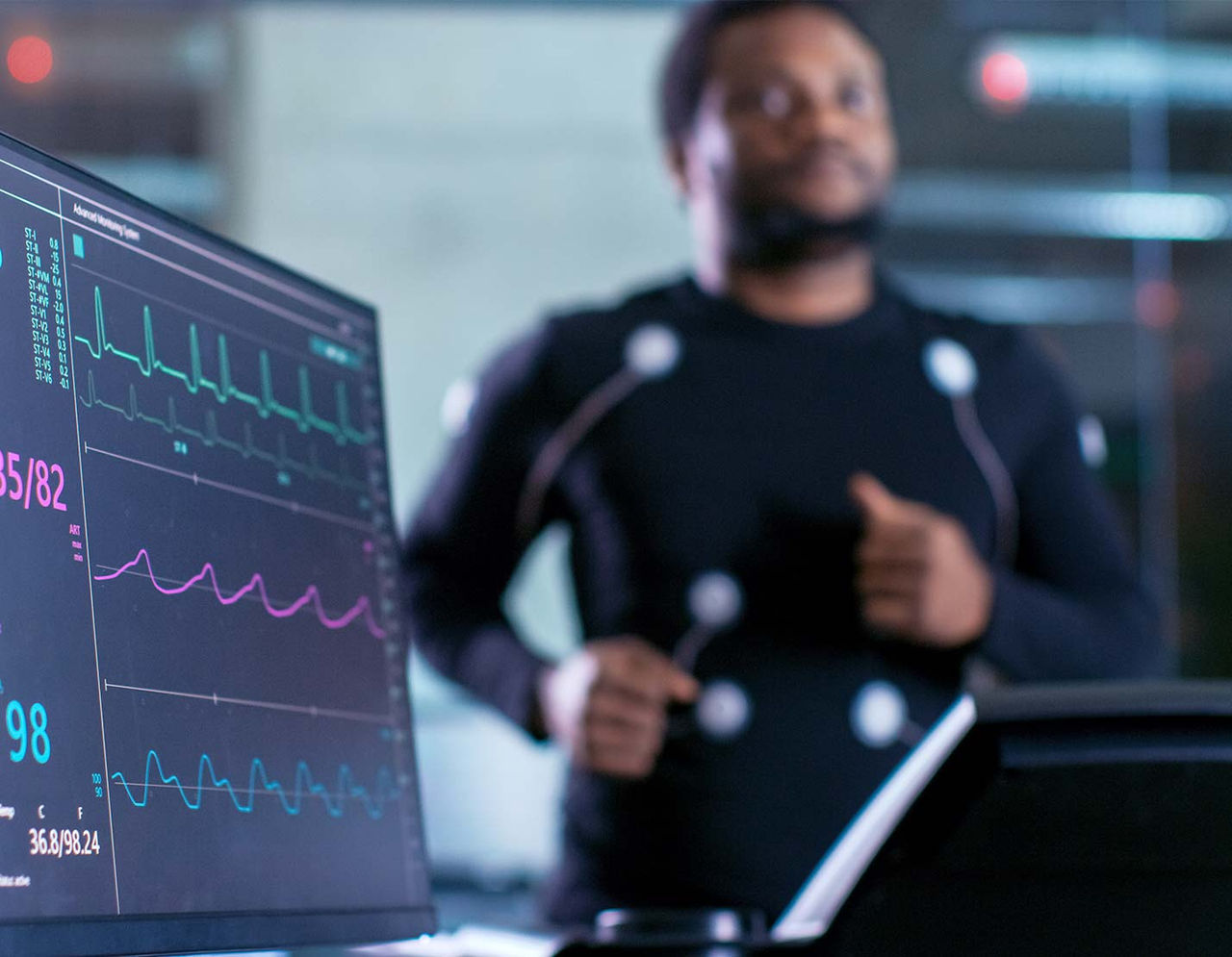 Man in motion suit with ECG monitor running on treadmill
