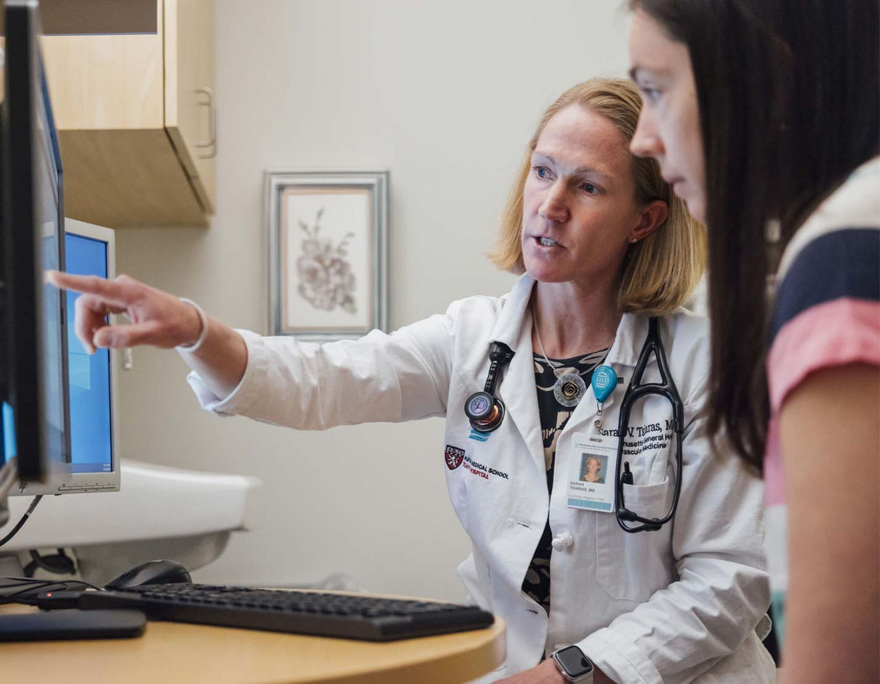 female heart provider pointing at monitor with female patient in exam room 