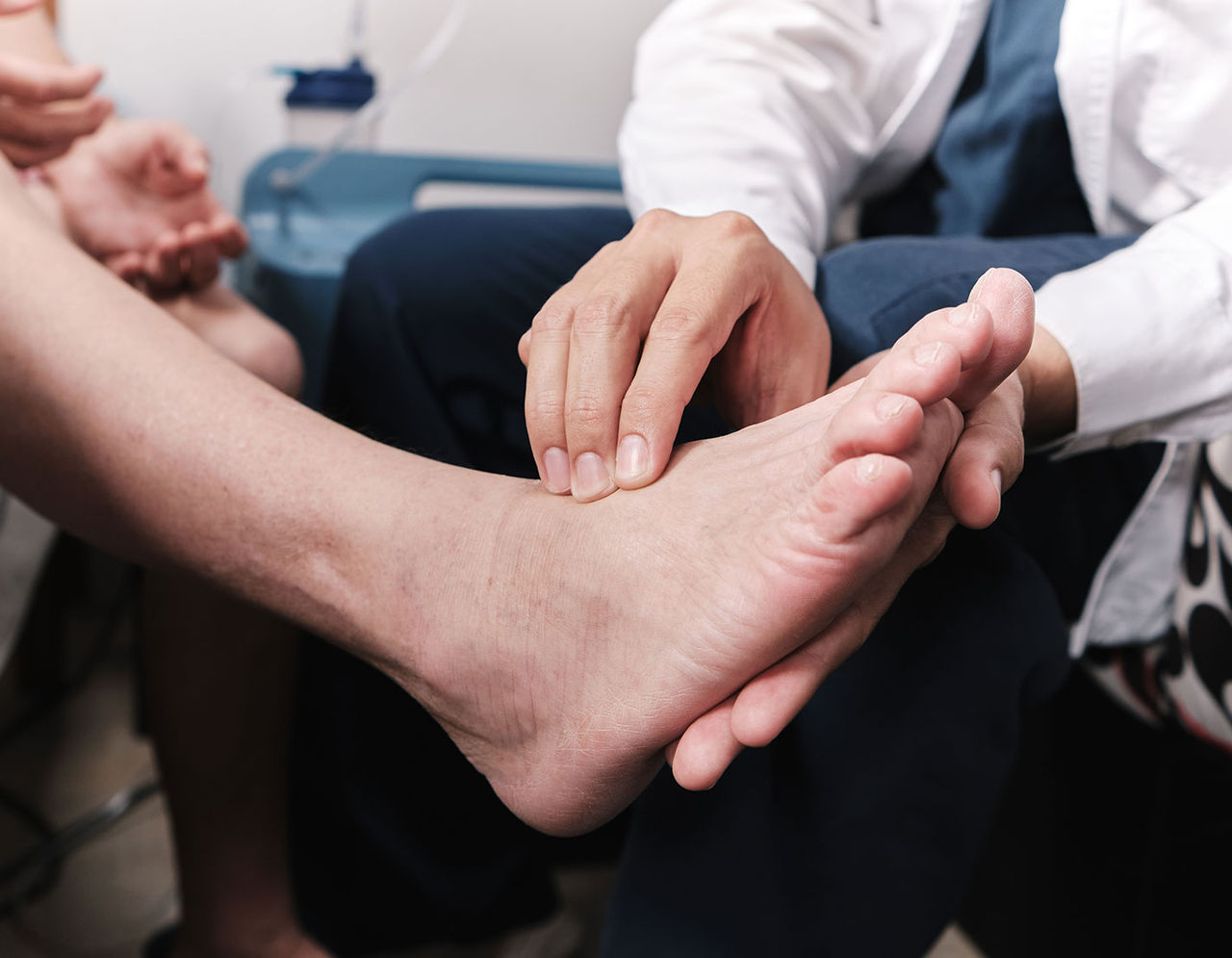 A healthcare provider carefully examines a patient's foot in a clinical setting