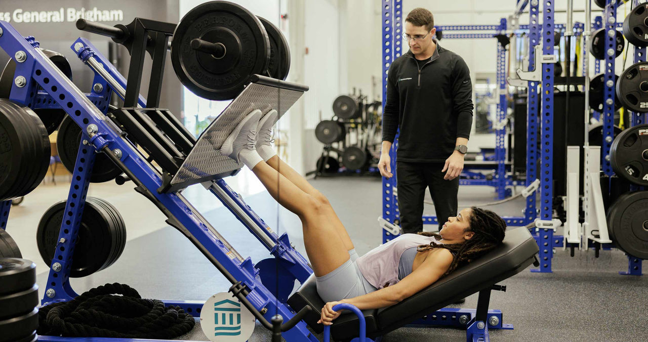 male trainer supervising a male athlete on running equipment in gym
