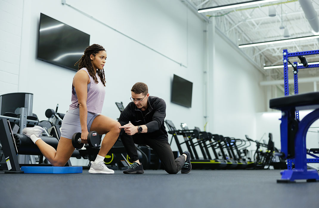 woman doing a squat with barbell on her shoulders at gym