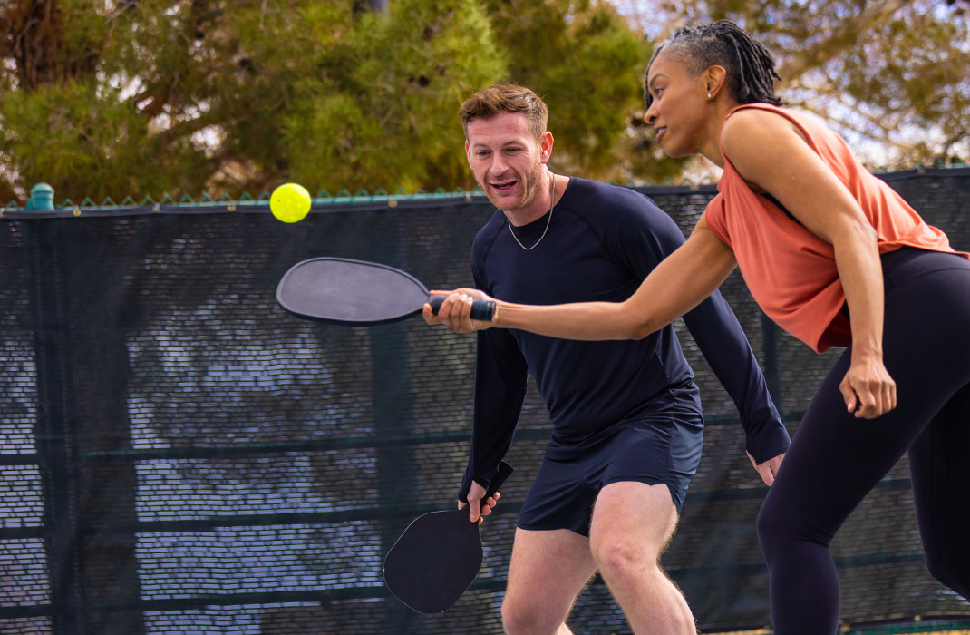 man and woman playing pickle ball on court
