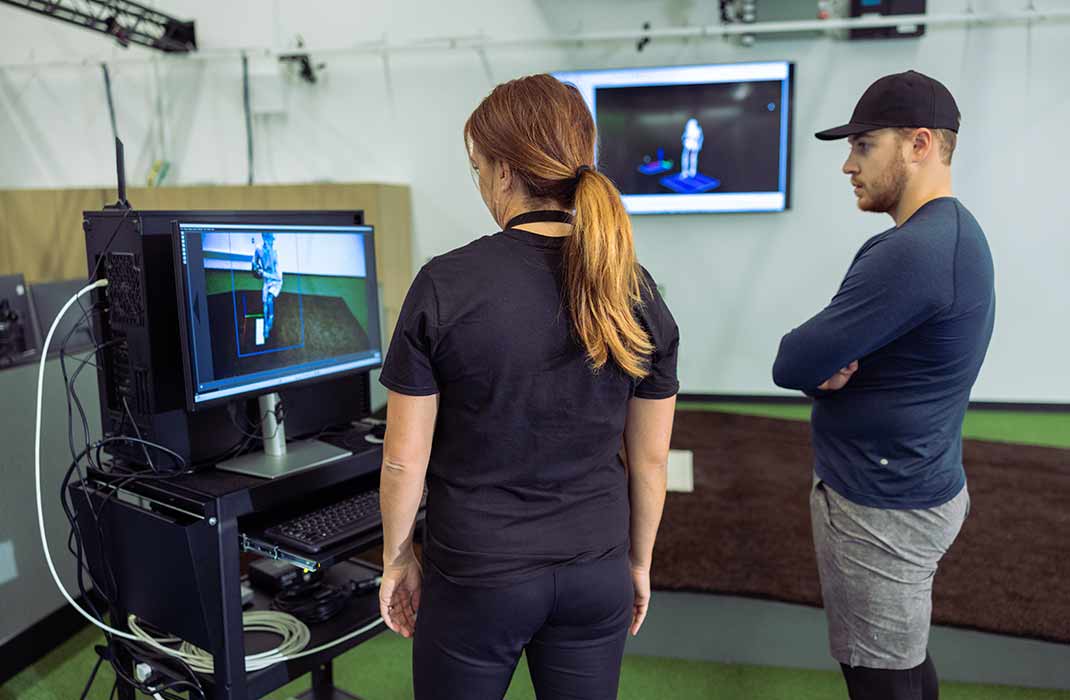 male athlete and female trainer looking at monitor in gym