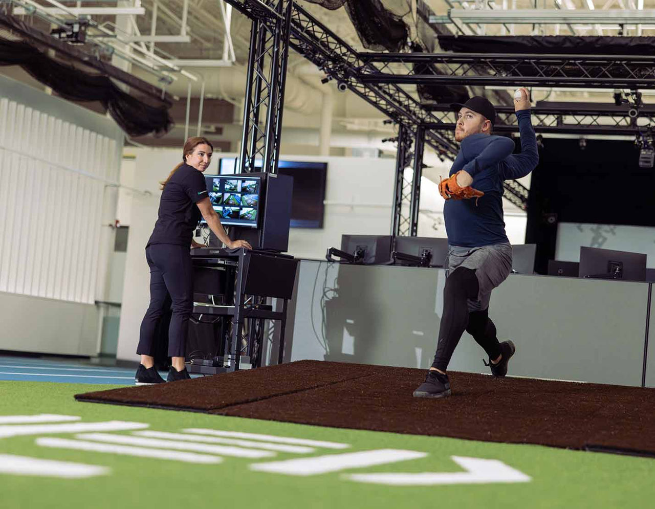 athlete throwing a baseball during a pitching assessment in gym