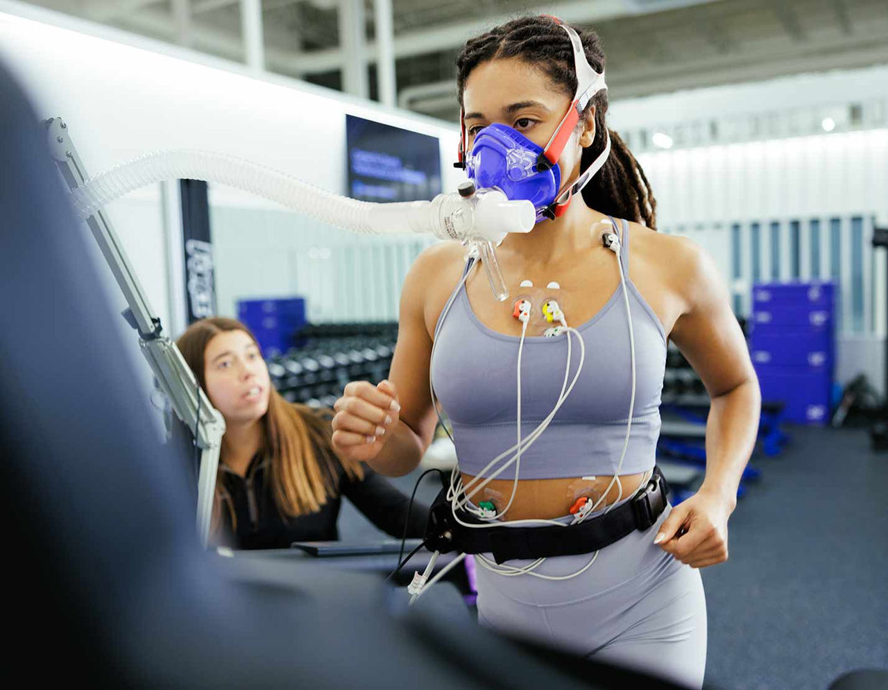 woman on treadmill with oxygen mask attached undergoing a fitness assessment