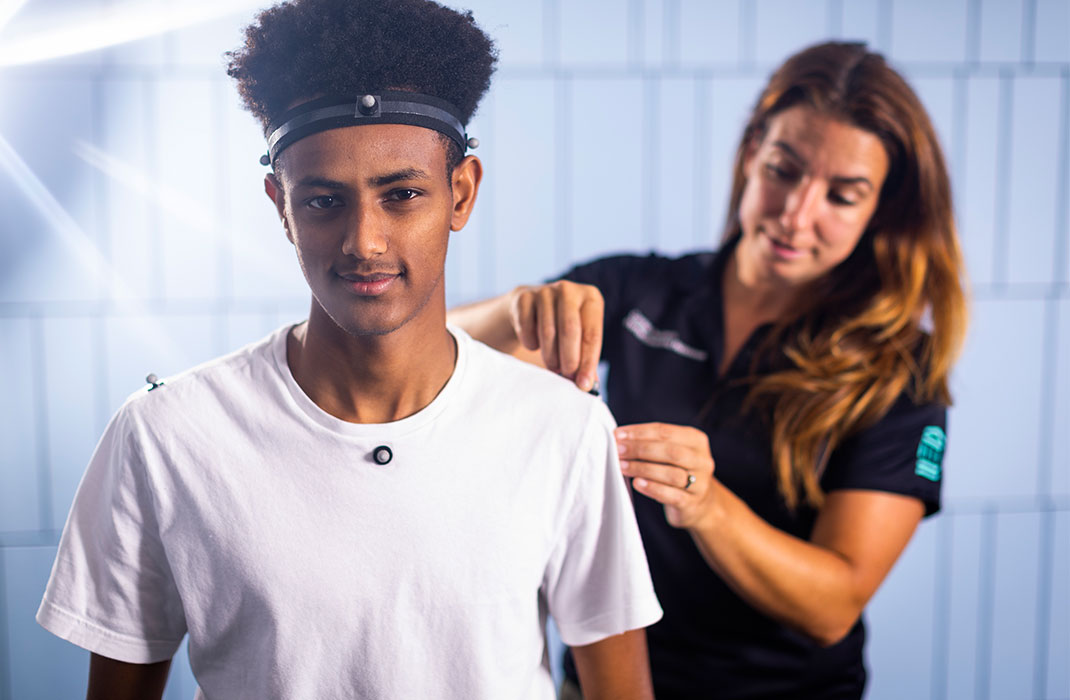Beth Wilcox adjusting sensors on the shoulder of a male client