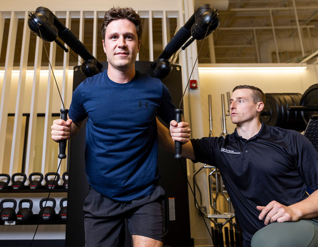 male athletic trainer supervising client on weight machine