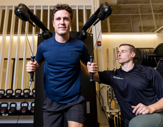 male trainer with male athlete in gym doing exercise