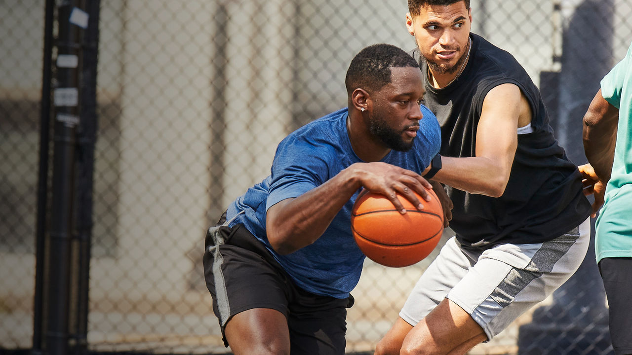 two men playing basketball outdoors 