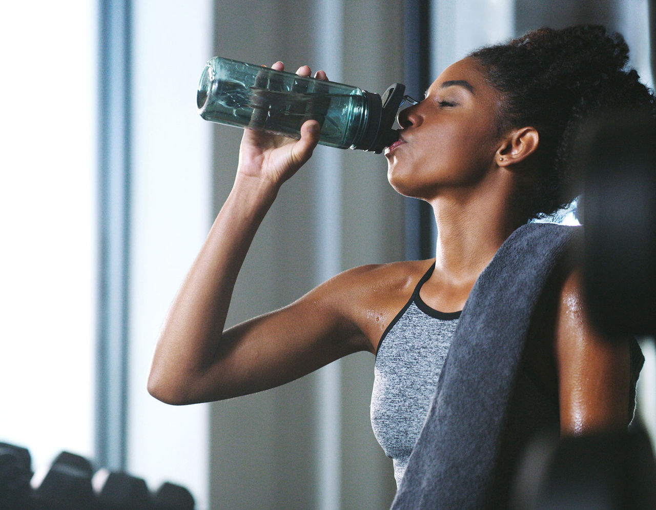 woman drinking water from bottle at gym