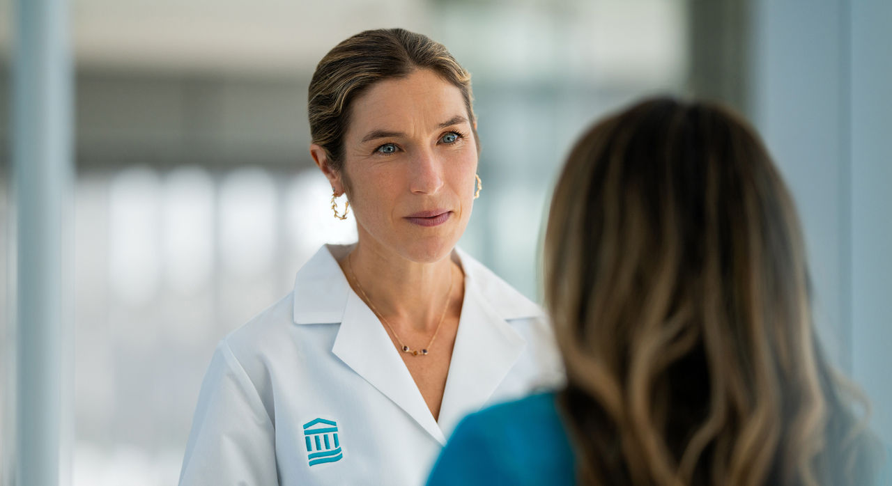 Sarah Wakeman in white coat listening