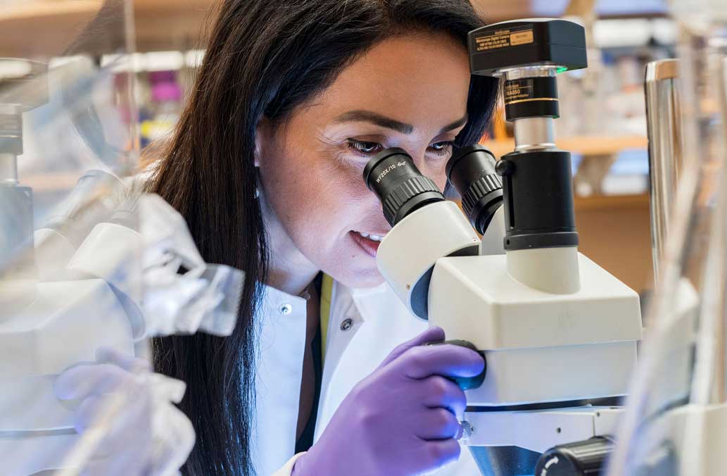 female scientist looking through microscope