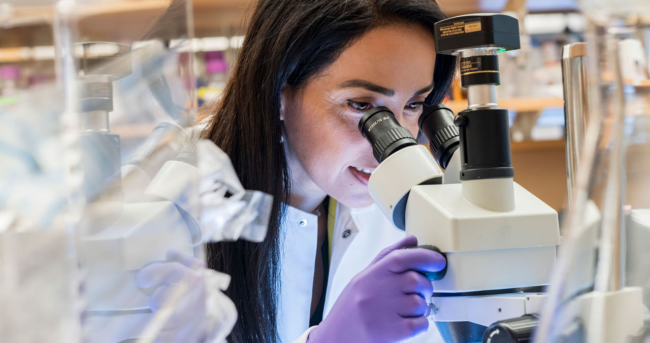 female scientist looking through microscope