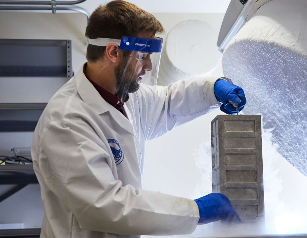 male researcher in lab removing a container from freezer