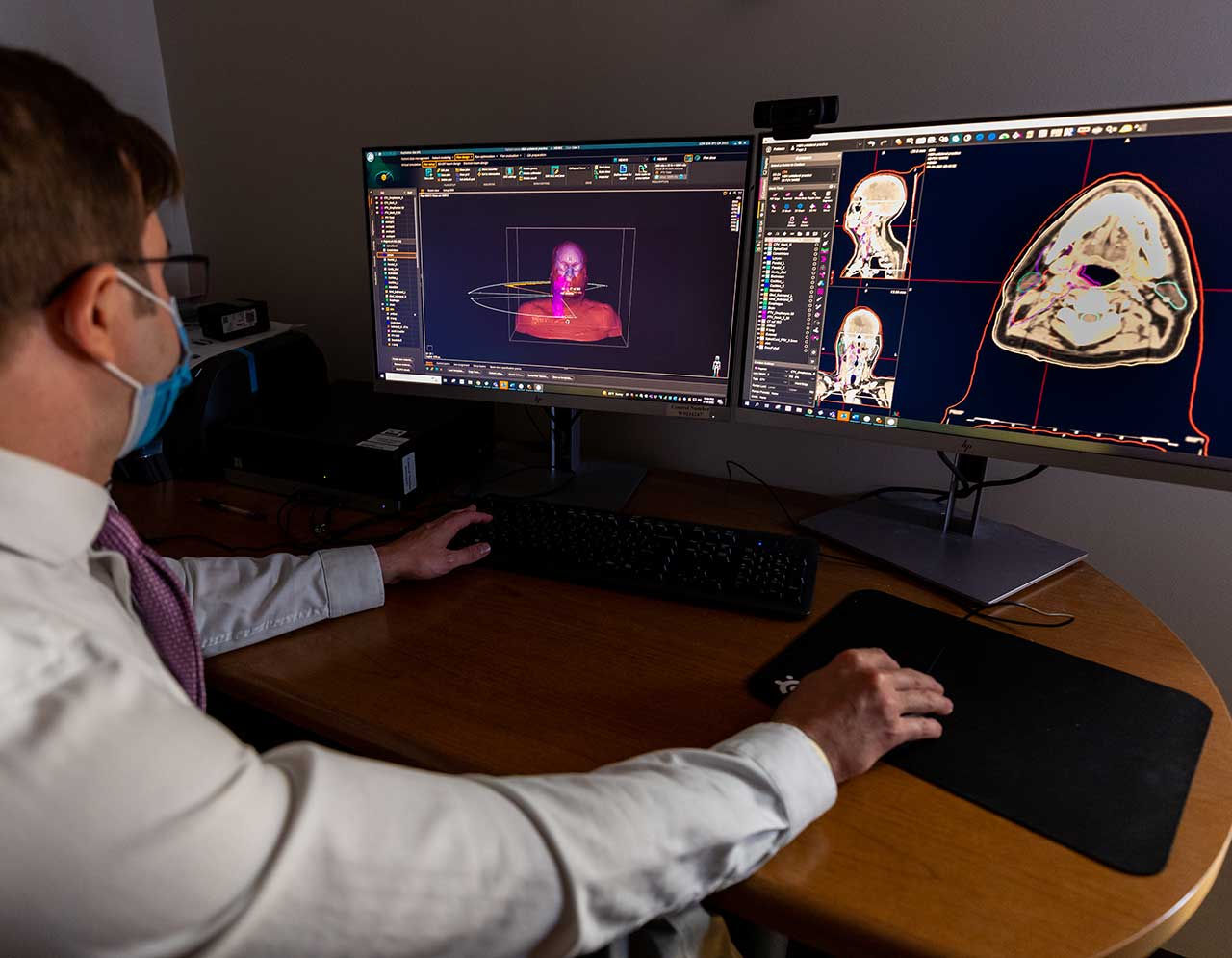 Man reviewing radiology scans on two screens.