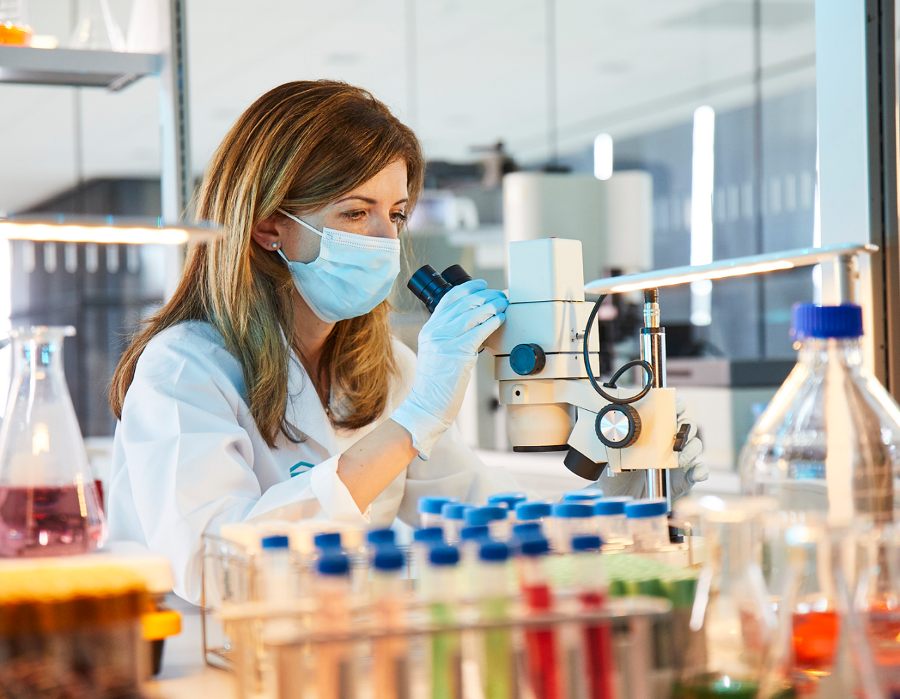female researcher looking in microscope in lab
