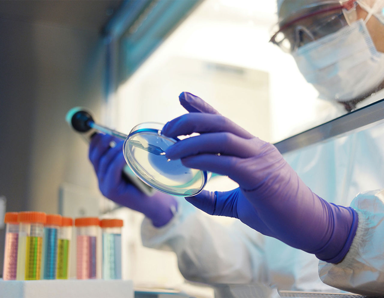 researcher in lab viewing sample under magnifiying glass