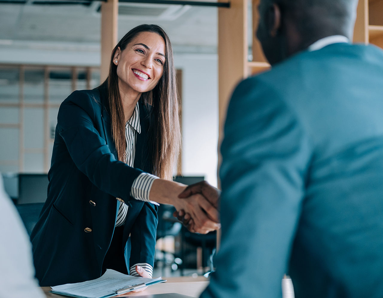 Business people shaking hands in the office. Group of business persons in business meeting. Three entrepreneurs on meeting in board room. Corporate business team on meeting in modern office. Female manager discussing new project with her colleagues. Company owner on a meeting with two of her employees in her office.