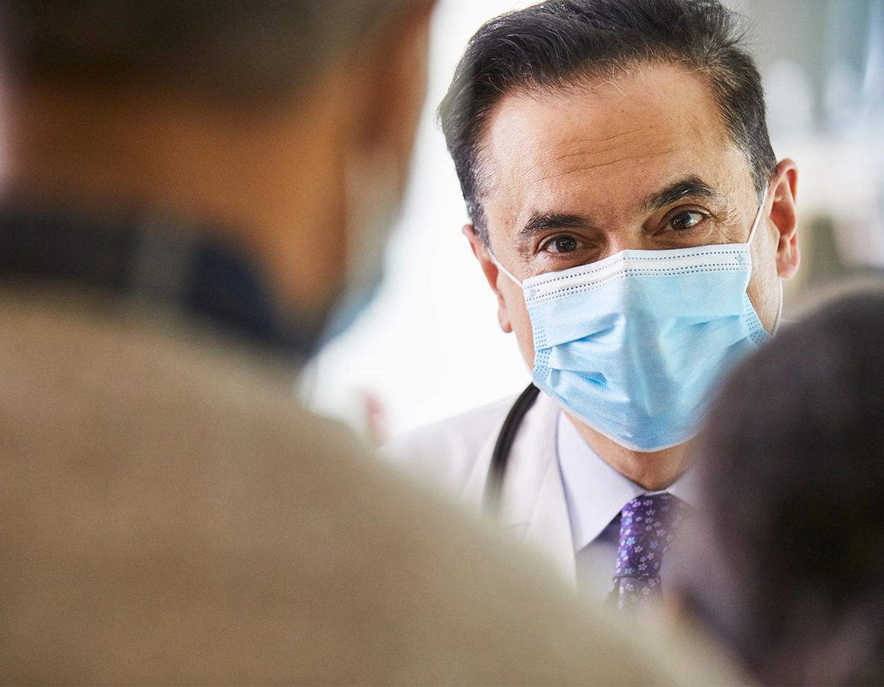 A doctor with a mask on chatting with patients