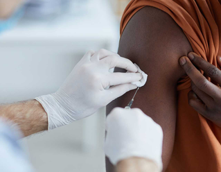 man receiving a flu shot on his arm from clinician