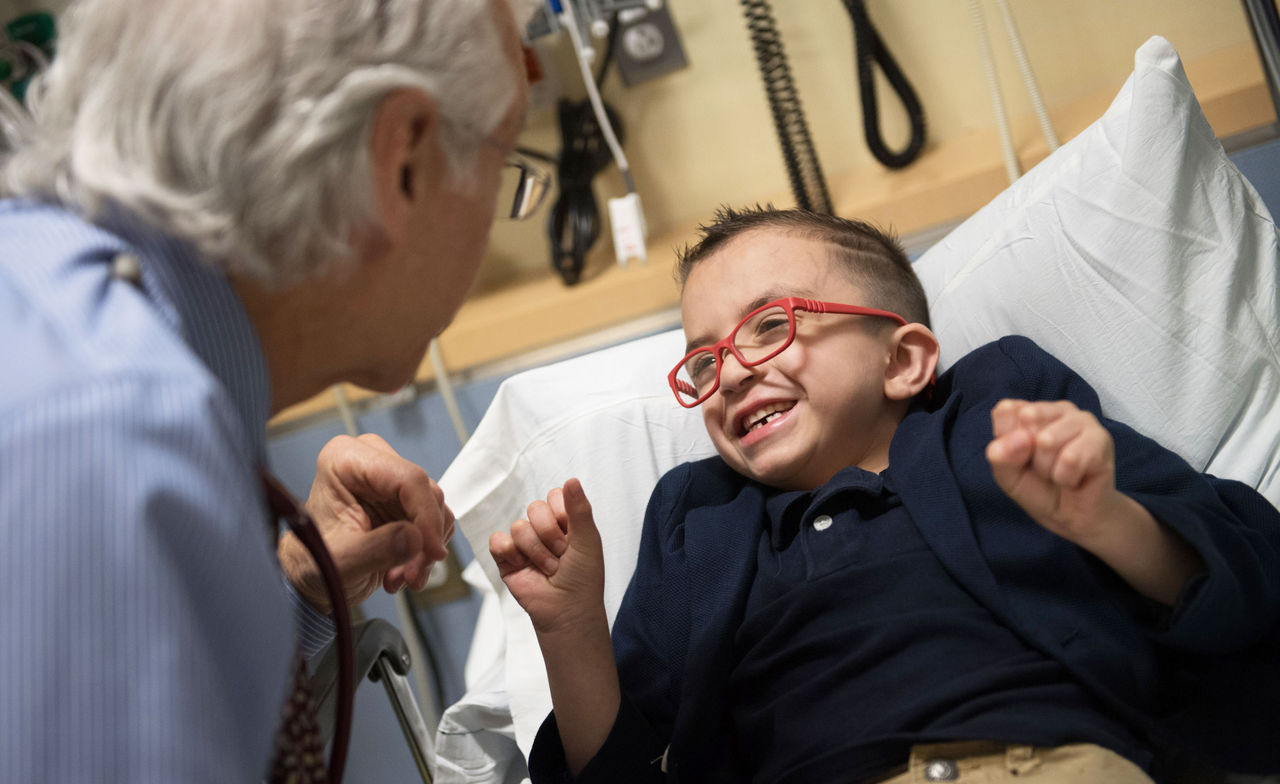 El Dr. Howard Weinstein sonríe con un paciente de oncología pediátrica