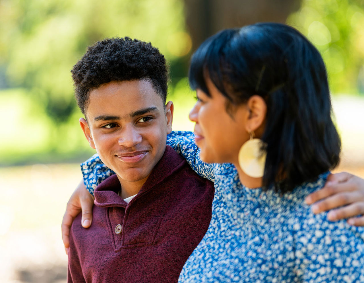 A Latino mother and son with their arms around each other's shoulders affectionately.