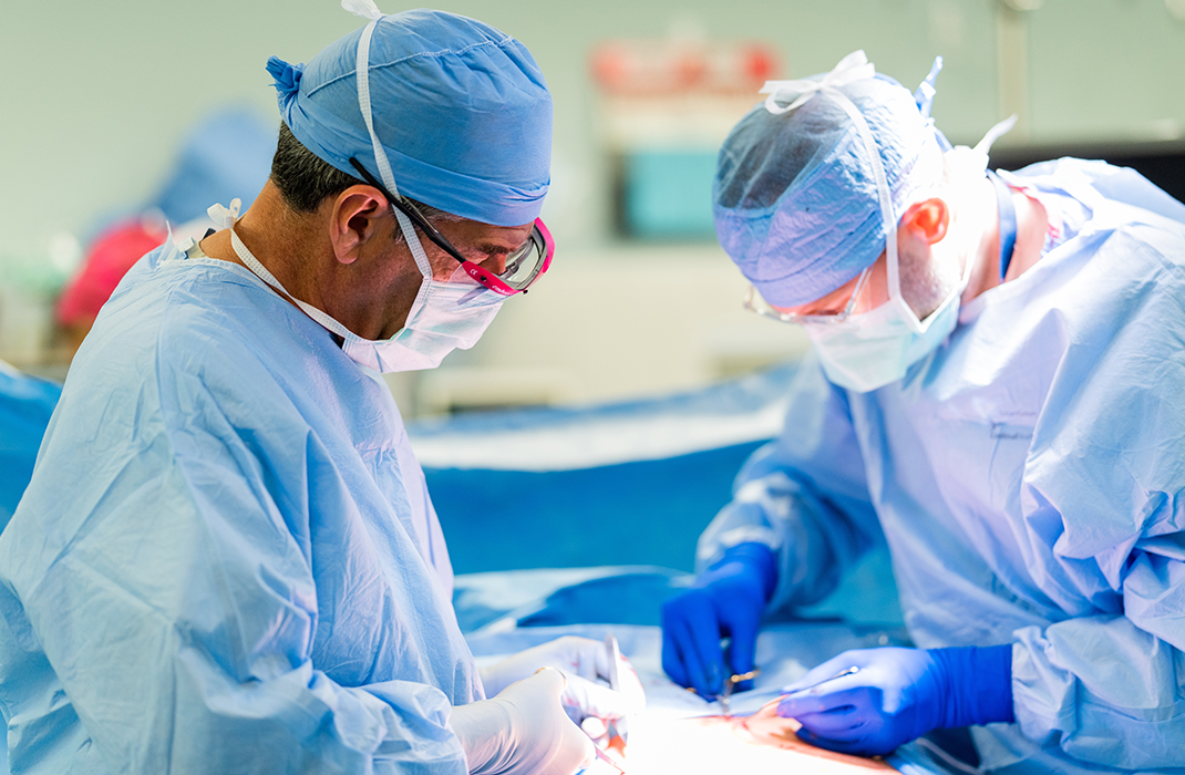 two male surgeons performing surgery on patient in operating room