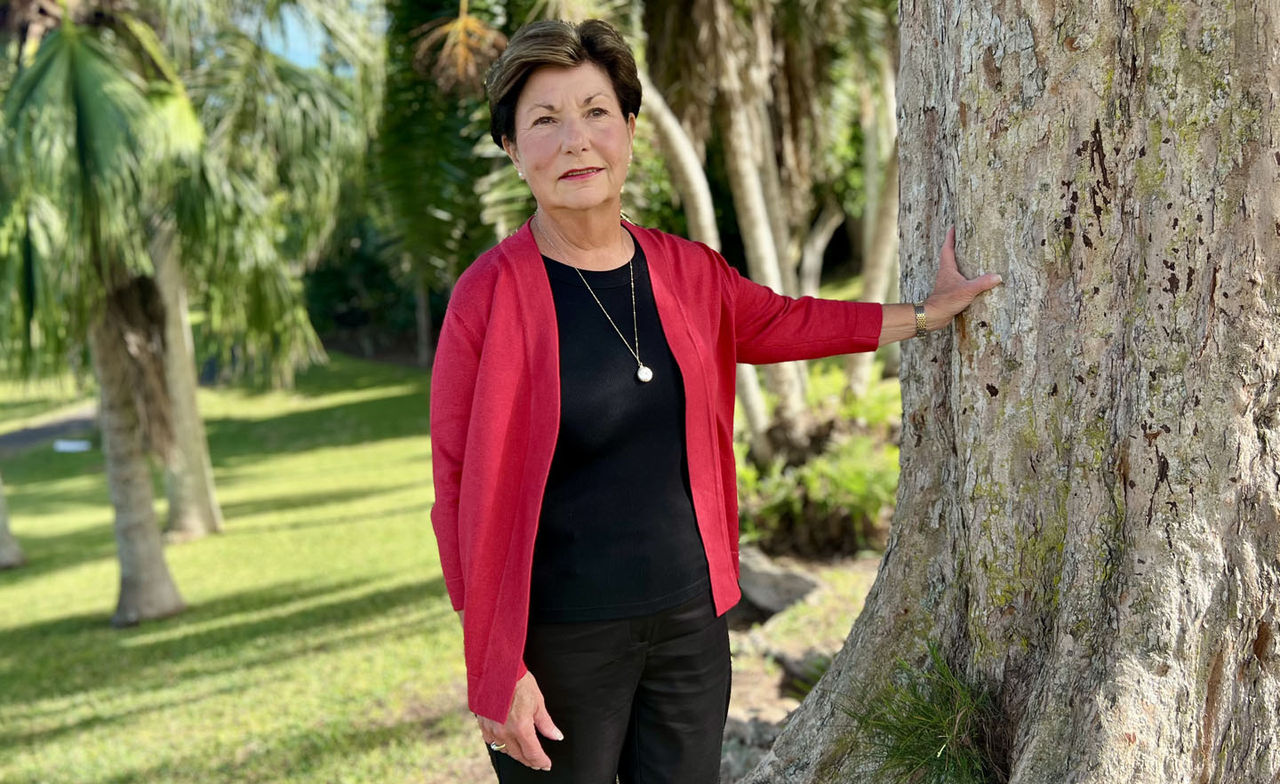 Penelope Perry靠在树上拍照，摆出拍照的姿势。